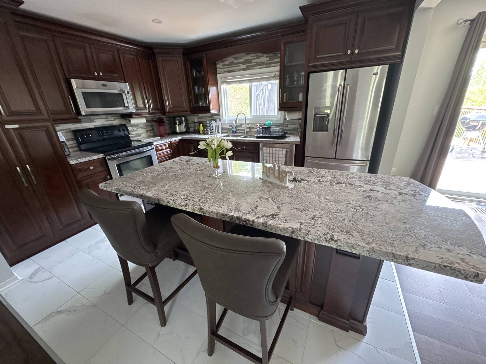 Kitchen with a large granite island and seating in the Innisfil cottage
